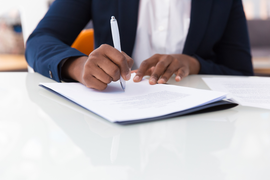 Serious businessman and businesswoman signing contract in boardroom. Young Caucasian female secretary showing papers to executive. Partnership concept